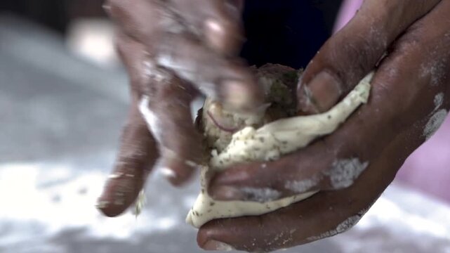 Skilled hands shaping layered dough for authentic laccha paratha preparation.