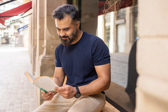 Indian man reading a book outdoors in an urban street