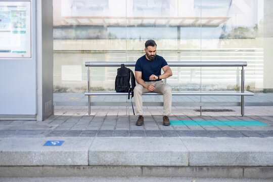 Indian man waiting at train station checking time, backpack
