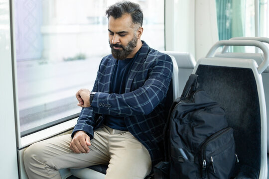 Indian businessman checking smartwatch on city train commute