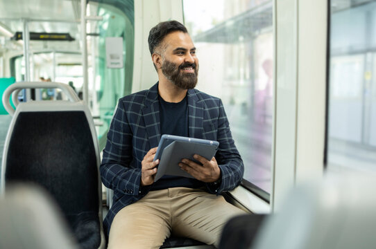 Indian businessman using tablet while commuting by train