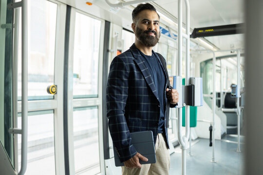 Indian businessman commuting on modern tram with tablet