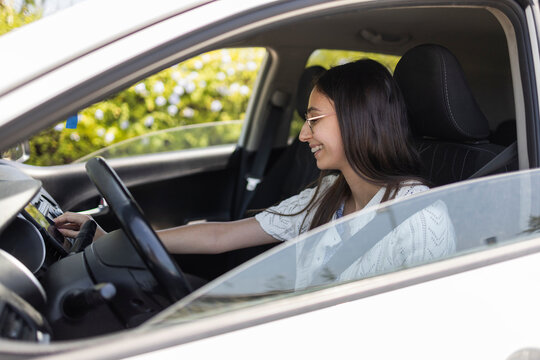 Smiling woman using car touchscreen while seated in driver seat