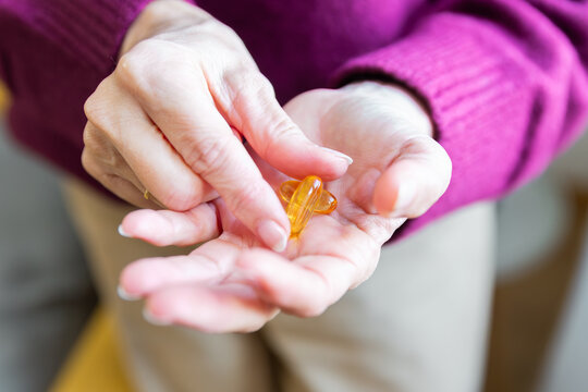 Senior woman taking omega-3 softgel as daily wellness