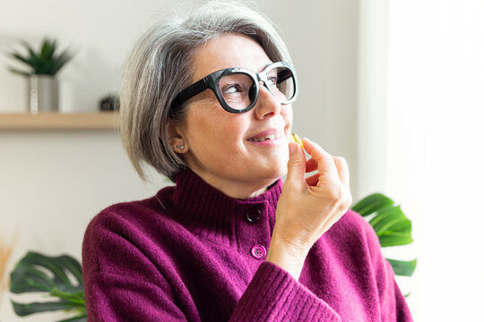 Senior woman taking vitamin at home for daily wellness