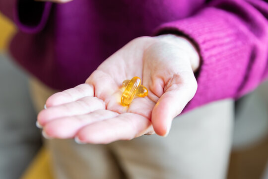 Senior woman holding vitamin supplement capsules at home