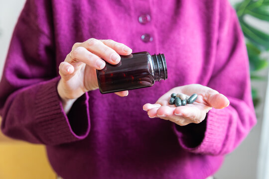Senior woman taking supplement capsules for daily wellness