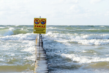 Polski znak na falochronie: Zakaz wchodzenia na ostrogi, skakania do wody, pływania przy ostrogach. Wzburzone morze, duże fale. Bałtyk, Polska © AFilipczuk