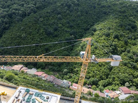 Construction crane overlooking lush forest and buildings