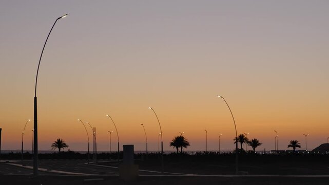 Quiet desert landscape before sunrise with empty roads, distant palm trees and mountains under soft dawn sky creating peaceful liminal atmosphere and cinematic travel background