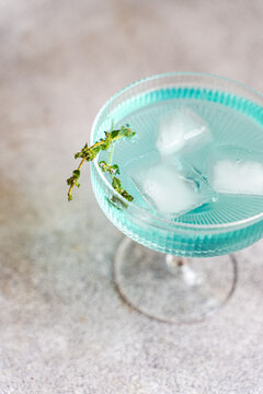 Refreshing blue cocktail with ice in coupe glass closeup