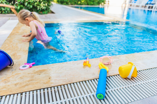 Toddler girl playing in a swimming pool with water toys