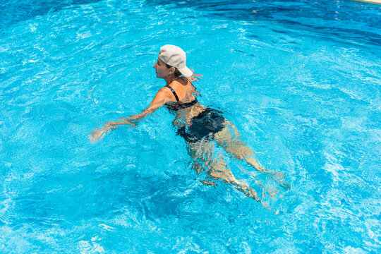Woman enjoying summer swim in clear blue pool