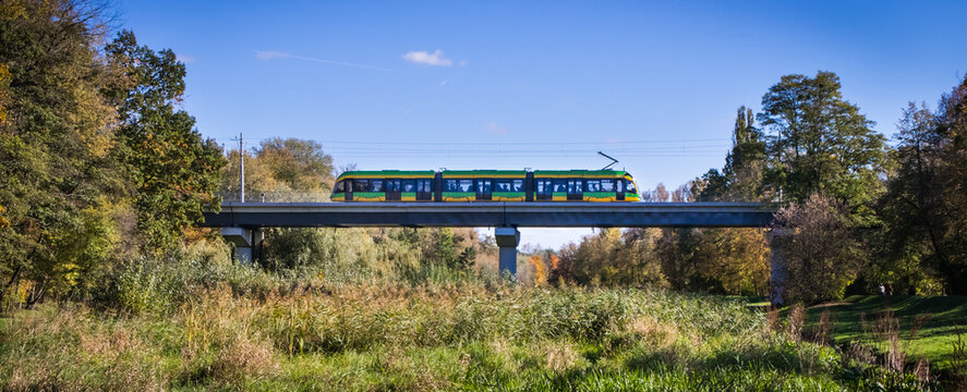 Poznan, Poland - October 19, 2025: Tram Moderus Gamma on tracks on bridge in Wodziczki Park in Poznan. Efficient, modern public transport in large city