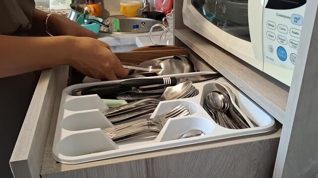 Organizing utensils in a kitchen drawer in a home setting