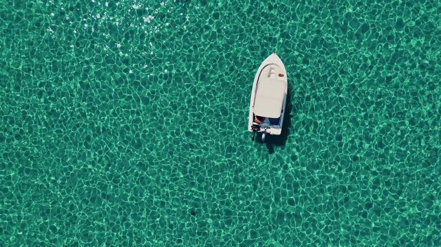 Motorboat Floating on Crystal Clear Turquoise Water in a Calm Lagoon, Aerial Pull Back