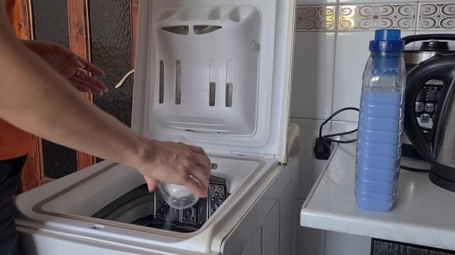 pouring laundry detergent into the drum of a top-loading washing machine