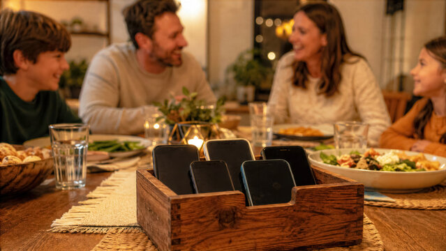 Family dinner with smartphones placed in a no phones basket in the center for social connection and detox