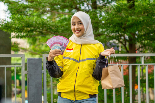 Asian muslim woman online motorcycle taxi drivers is holding money. Earning money from their work. Illustration for world women day.