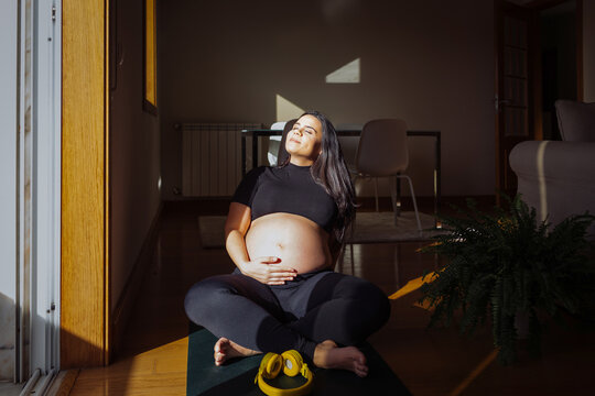 Pregnant woman relaxing in sunlight after prenatal yoga