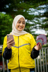 Naklejka premium Asian muslim woman online motorcycle taxi drivers is holding money. Earning money from their work. Illustration for world women day.