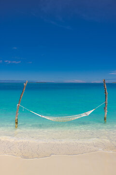 Peaceful hammock swing white sand beach turquoise ocean lagoon, sunny blue sky paradise island coast vertical. Summer vacation travel relax tropical holiday getaway background wallpaper landscape