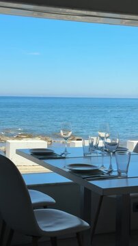 Empty served restaurant table with sea view. Luxury fine dining terrace on Mediterranean coast on a sunny day