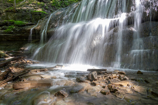 Serene view of Sherman Falls cascading over rocks in Hamilton, Ontario, surrounded by lush greenery.