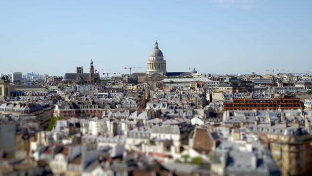 Panoramic view over Paris rooftops with the Panth&eacute;on rising above the city skyline on a clear sunny day.