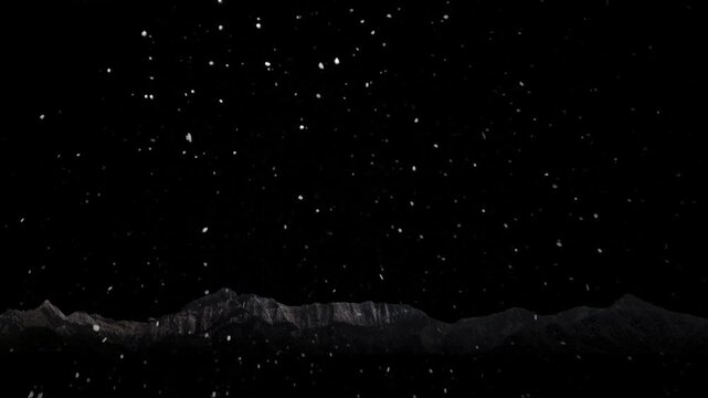 Snow is falling against the backdrop of mountains and a black background