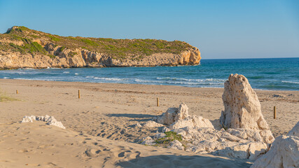Large white limestone rocks on a sandy beach at the foot of a steep hillside  © Veronika