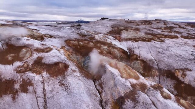 Drone panorama of snow covered volcanic and sulfur-stained hills with thermal vents