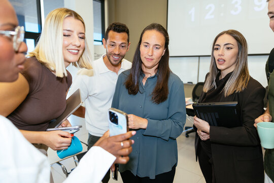 Business colleagues collaborating using smartphone in office meeting