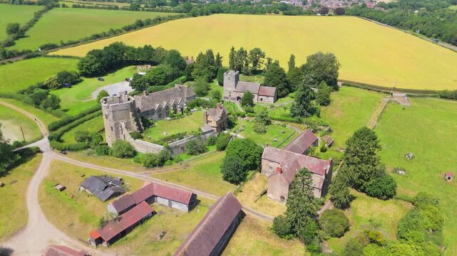 Aerial drone orbit of the part ruins of the 13th Century, Stokesay Castle in Shropshire, UK with the Church of St John the Baptist at the back