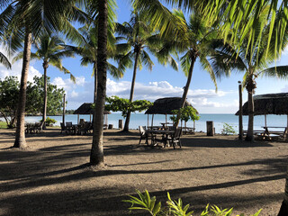 Beachfront picnic area with thatched fales in evening light © VJH Photography