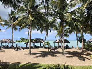 Beachfront picnic fales under palm trees beside turquoise lagoon © VJH Photography