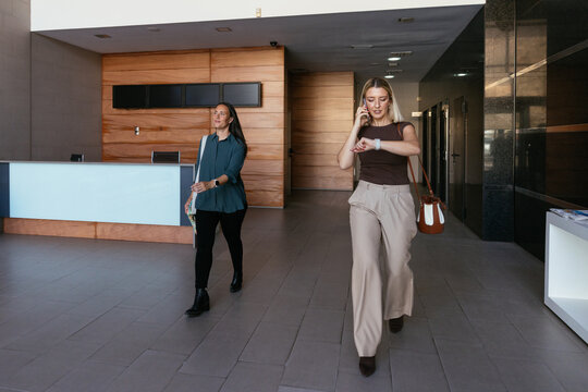 Businesswomen walking through modern office lobby 