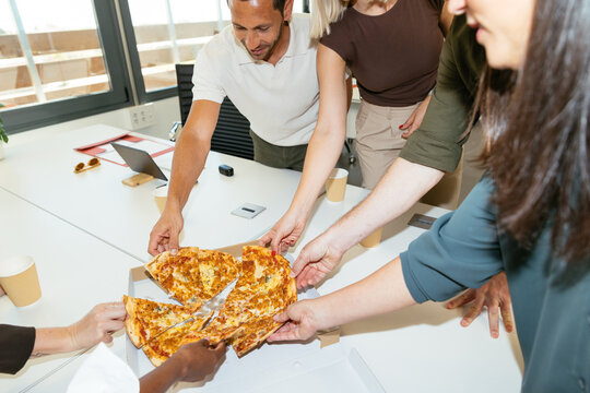 Coworkers sharing pizza during office lunch break
