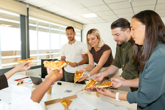 Coworkers sharing pizza slices during office lunch break