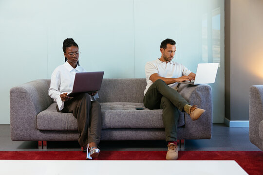 Professionals working on laptops in modern office lounge area
