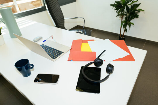 Office desk with laptop, tablet, headset, and files