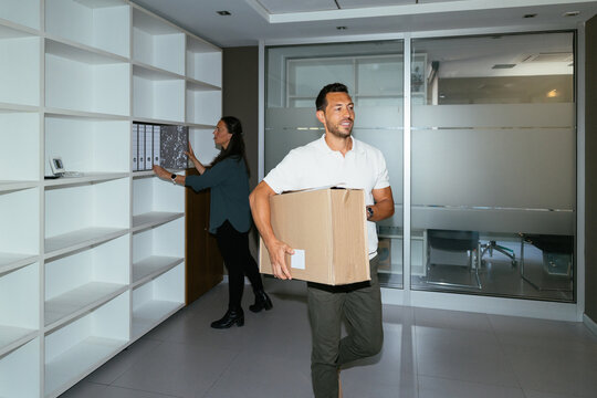 Coworkers moving office, carrying box and organizing files