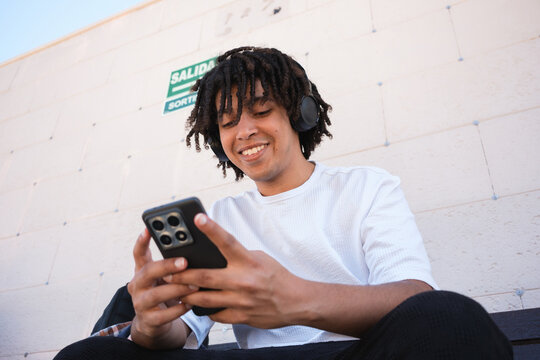 Young Man Enjoys Music While Using Smartphone Outdoors