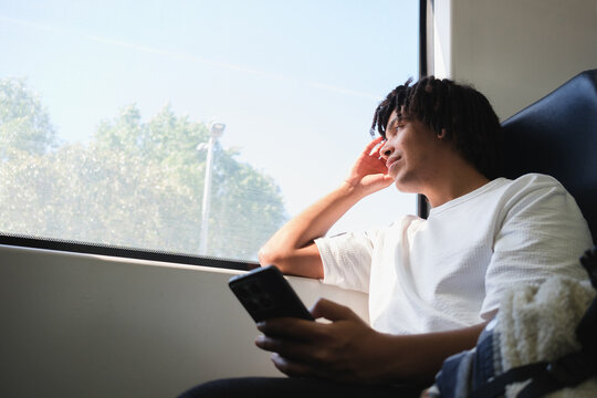 Man Looking out of Train Window While Holding Phone. Copy space
