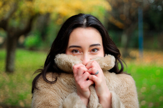 Young woman hiding behind her collar