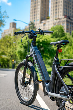 New York, USA, 1 April 2026: Electric rental bike parked on Central Park path. Segway electric bicycle standing on asphalt path with San Remo towers and green trees in background New York.
