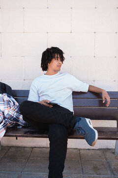 Young Man Sitting on a Bench With a Phone in a Relaxed Pose
