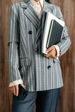 Businesswoman Holding Notebooks and Smartphone in Plaid Blazer