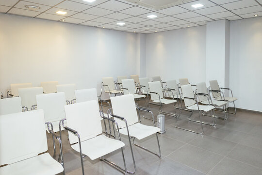 Empty modern conference room displaying rows of white chairs