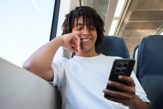 Young Man Smiles While Using Smartphone on Public Transport